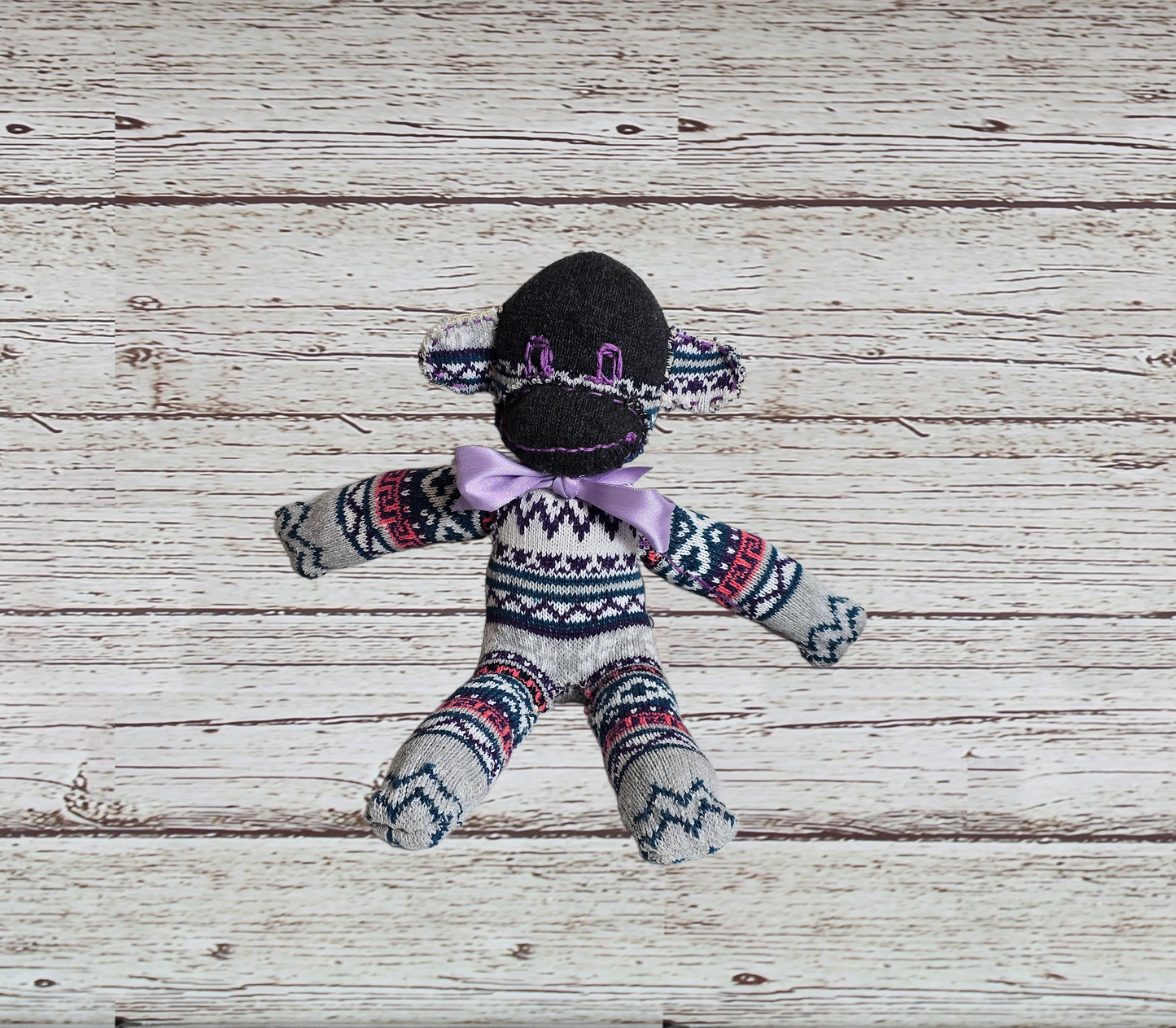 Sock monkey toy with patterned sweater on a wooden surface