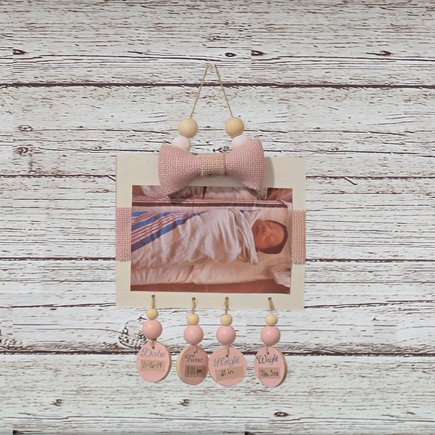 Decorative wall hanging with pink elements on a wooden background