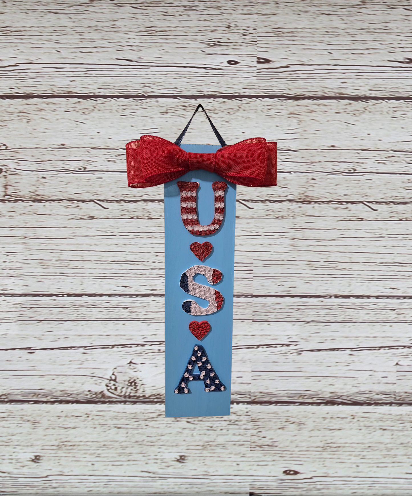 Decorative sign with 'USA' and red bow on a wooden background