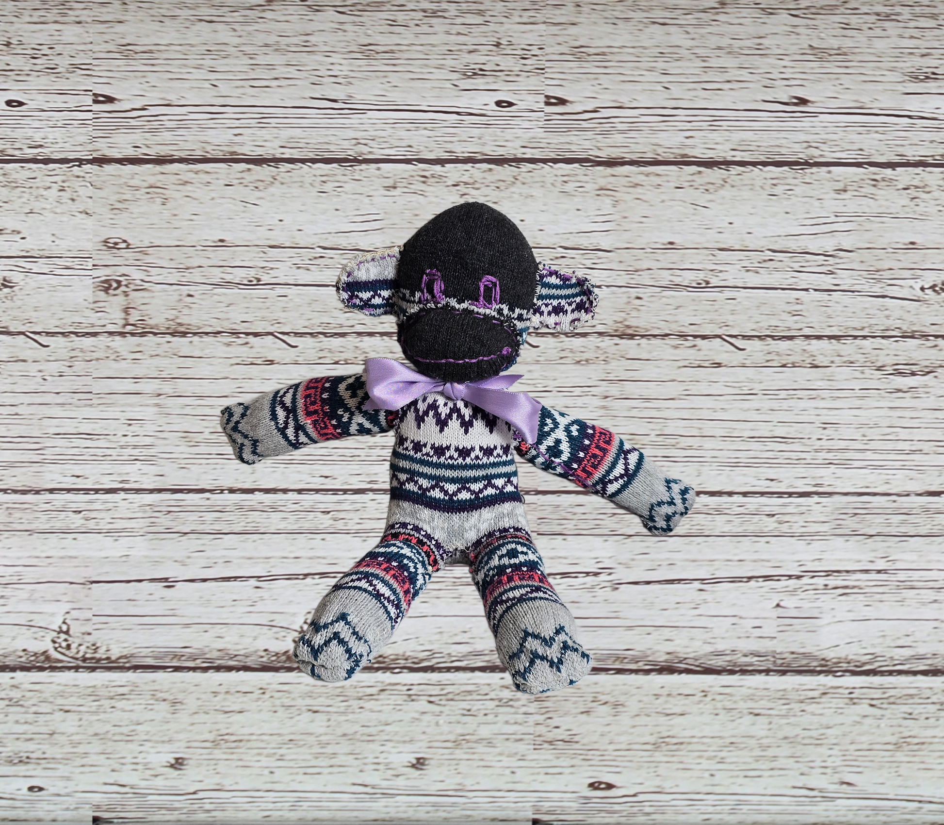 Sock monkey toy with patterned sweater on a wooden surface