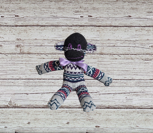 Sock monkey toy with patterned sweater on a wooden surface