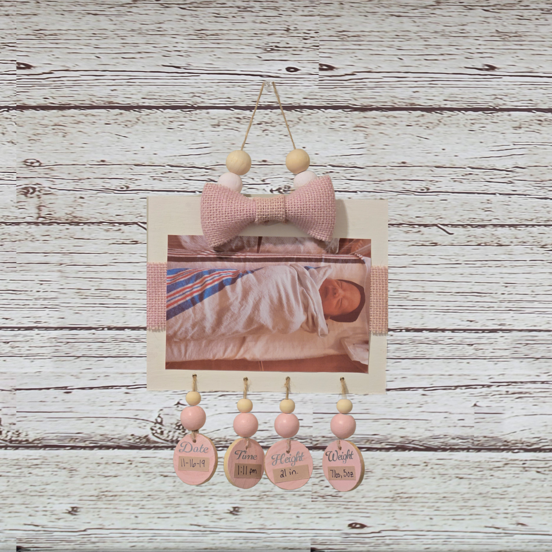 Decorative wall hanging with pink elements on a wooden background